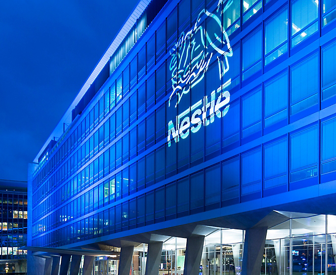 A building lit up at night with a Nestle logo on it