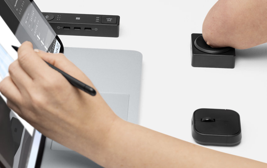 A person who has a physical disability uses Microsoft Adaptive D-pad Button and Hub with their Surface device. 