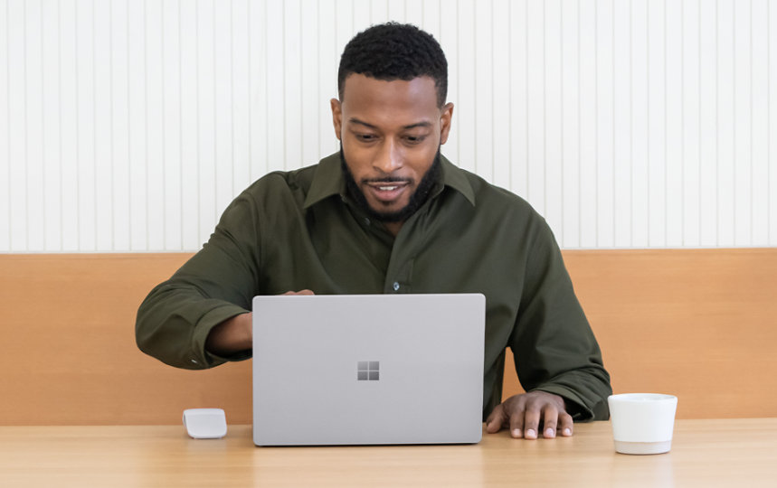 A man using a Surface Laptop 5 at a table.