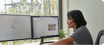 Un bărbat stând la un birou cu două monitoare și dispozitive mobile, lucrând de la distanță de la biroul său de acasă
