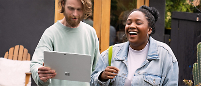 Un hombre y una mujer riendo mientras sostienen una tableta Microsoft Surface.