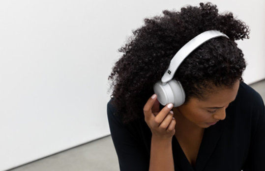 A woman touches the right side of her Surface Headphones 2.