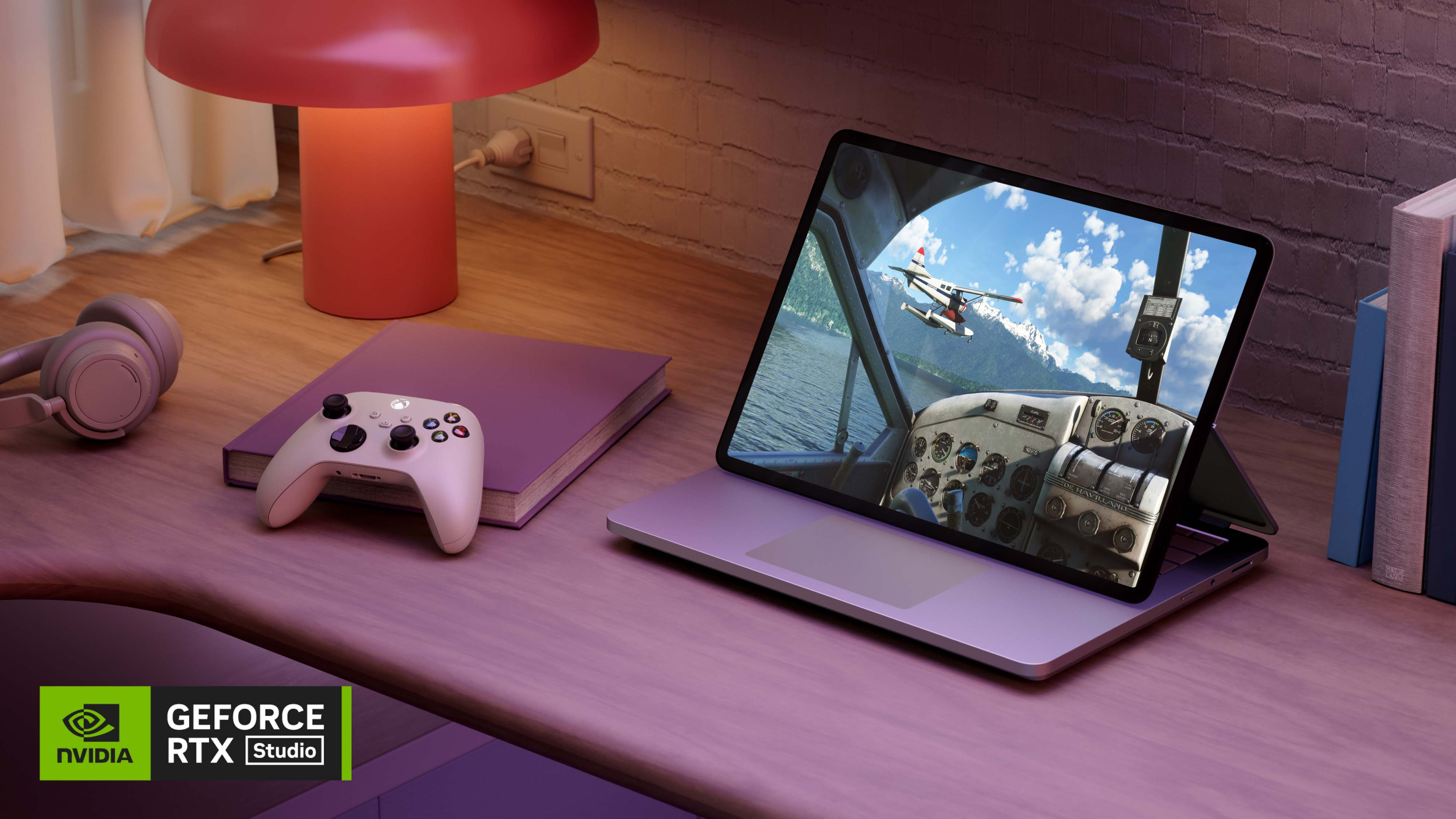 木製の机の上にヘッドホン、ゲーム コントローラーと本の横に置かれた、ステージモードの Surface Laptop Studio 2。