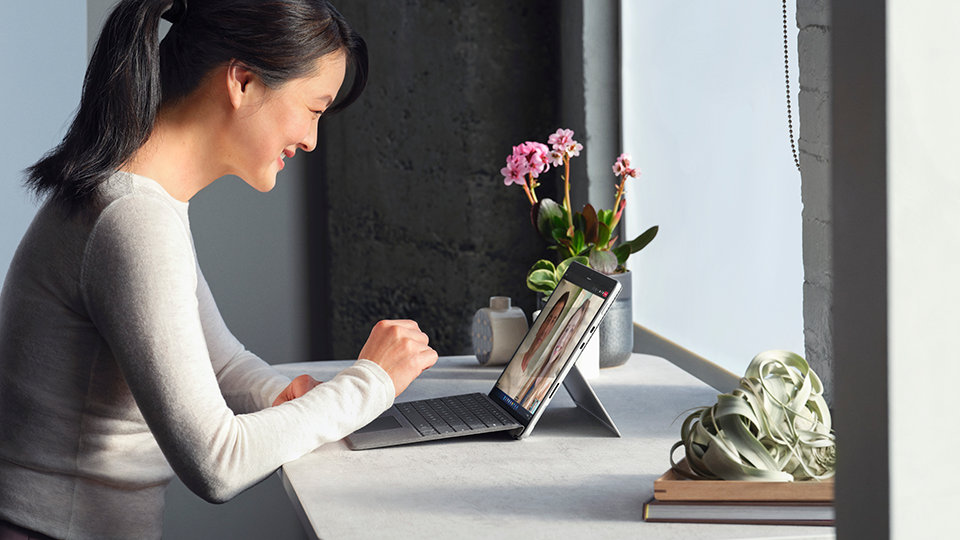 Une personne assise à un bureau, travaillant avec Surface Pro 8 pour les entreprises.