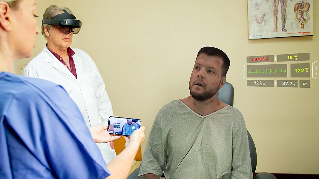 Two medical professionals using HoloLens 2 to meet with a patient.