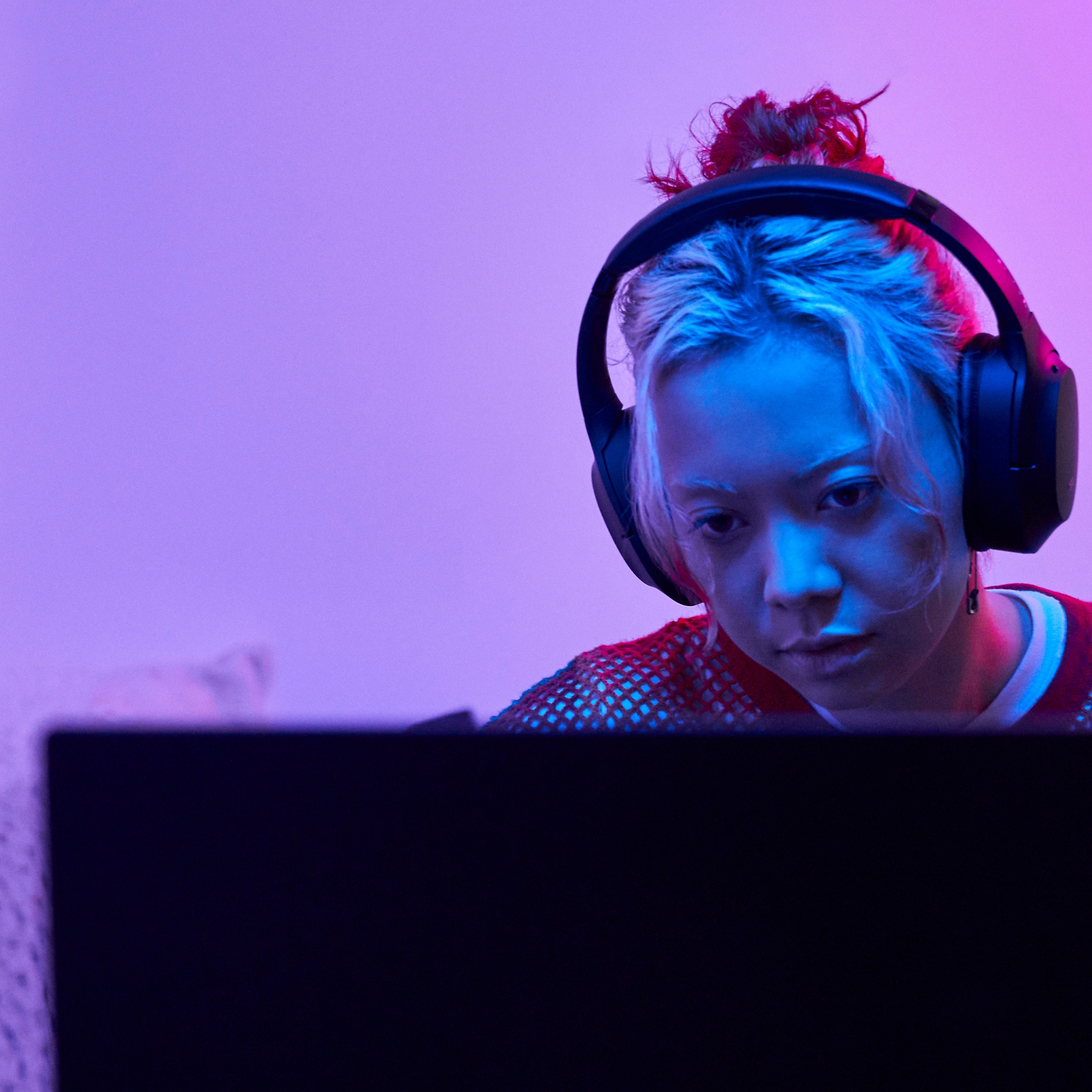Kvinna arbetar på en bärbar dator med hörlurar