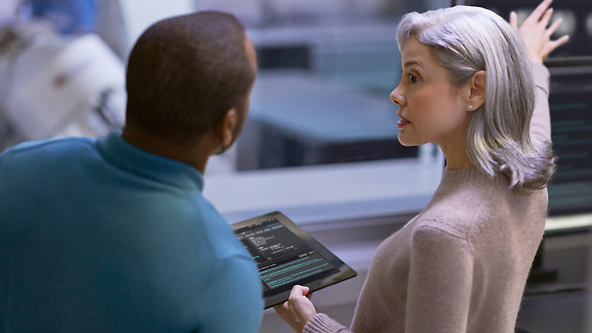 Um homem falando com a mulher segurando um tablet na mão