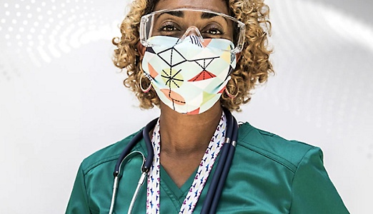 Önlük, stetoskop, koruyucu gözlük ve maske takan bir sağlık hizmetleri çalışanı.