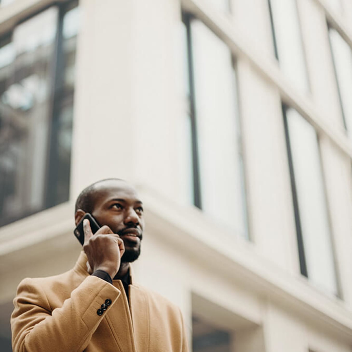 black man on phone outside, in front of a building