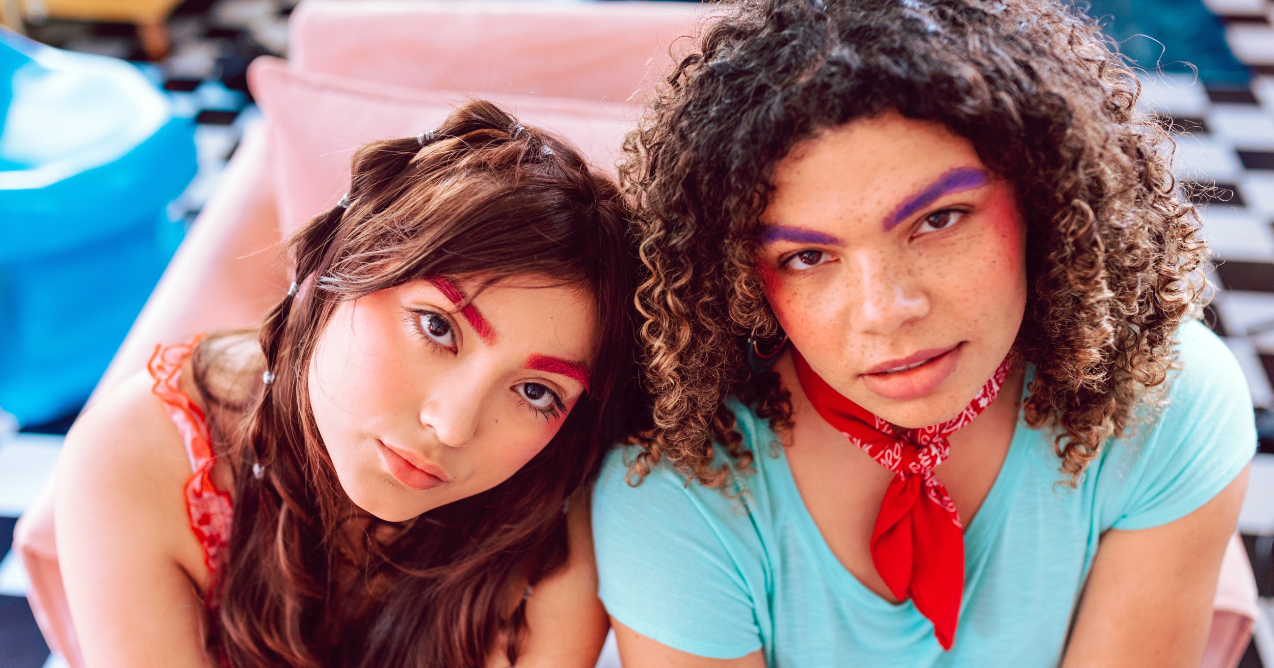 Two youth wearing colorful clothing stare into the camera