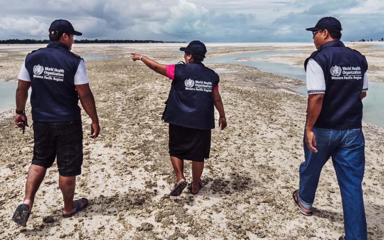 Three WHO staff are walking on the beach in South Tarawa, Kiribati.
