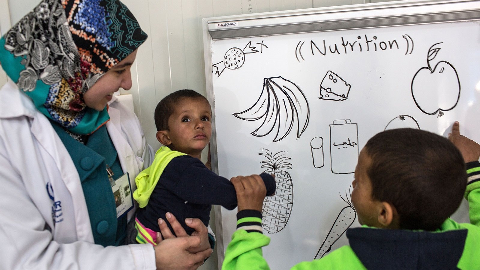Photo of a healthcare worker caring for two young boys in a Syria refugee camp.