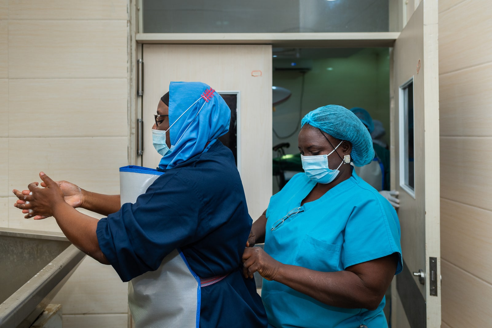 Dr Amina Abubakar Bello disinfects her hands as nurse Dorcas Samuel prepares her to go into the theater for a surgery in the Jummai Babangida Aliyu Maternal and Neonatal Hospital (JBAMN) in Niger State on 24 February 2021.