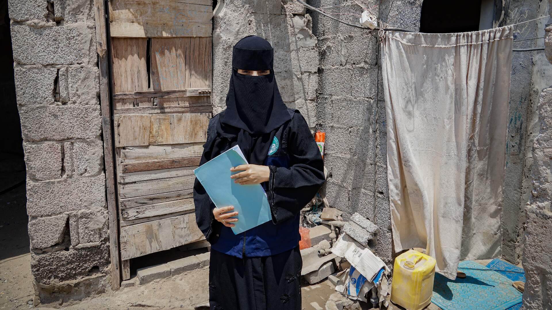 A female community health volunteer, dressed in a burqa, poses for the camera
