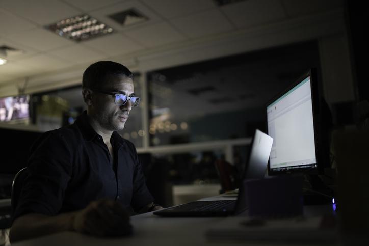 A person sits in front of a computer late at night.