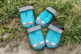 The Ruffwear Grip Trex, four boots in a vibrant shade of turquoise, with tough rubber soles and Velcro straps at the top.