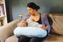 A woman breastfeeding a baby using a nursing pillow.