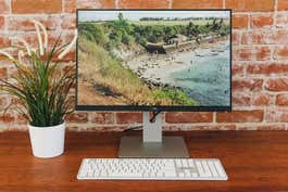 Another great pick for the best 24-inch monitor, the Dell UltraSharp U2415. The screen is on and displaying a photo of a beach.