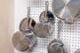 Pots and pans on peg board with lid threaded through handle