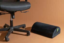 The ErgoFoam adjustable footrest shown next to an office chair.