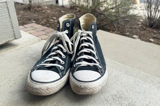 A pair of black, high-top Converse sneakers knotted with Bread Laces.