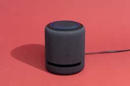 The Amazon Echo Studio bluetooth speaker, in front of a red background.