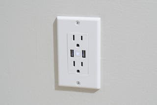The Geeni Current+Charge in-wall smart outlet, shown installed in a wall.