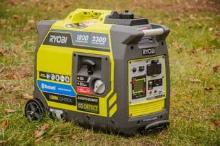 A Ryobi RYi2322VNM on a grassy lawn turned so that its start button and control panel are visible