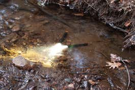 Two flashlights submerged in an outdoor stream.