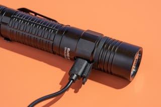 The ThruNite TC15 flashlight connected to the USB charging cable.