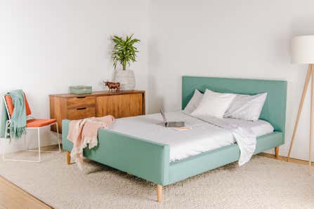 A pick we tested to find the best modern bed frames to dress up your bedroom, shown with throw blankets and crisp sheets.