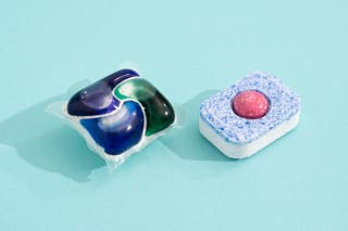 Two detergent pods, the Cascade Platinum Plus ActionPac (left) and Finish Powerball Classic Tab (right), against an aqua-colored backdrop. 