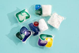An assortment of six different detergent pods laying against an aqua-colored backdrop.