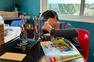 A kid building a Lego Medieval Castle.