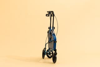 The Vive Health Three Wheel Walker Rollator, collapsed into its folded-up position, in front of a beige background.