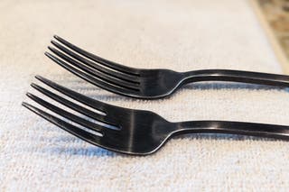 Two different black forks resting next to each other.