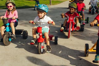 A group of kids riding tricycles.