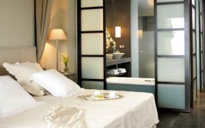 sypialnia z białym łóżkiem i łazienką w obiekcie Asia Gardens Hotel & Thai Spa, a Royal Hideaway Hotel w mieście Finestrat