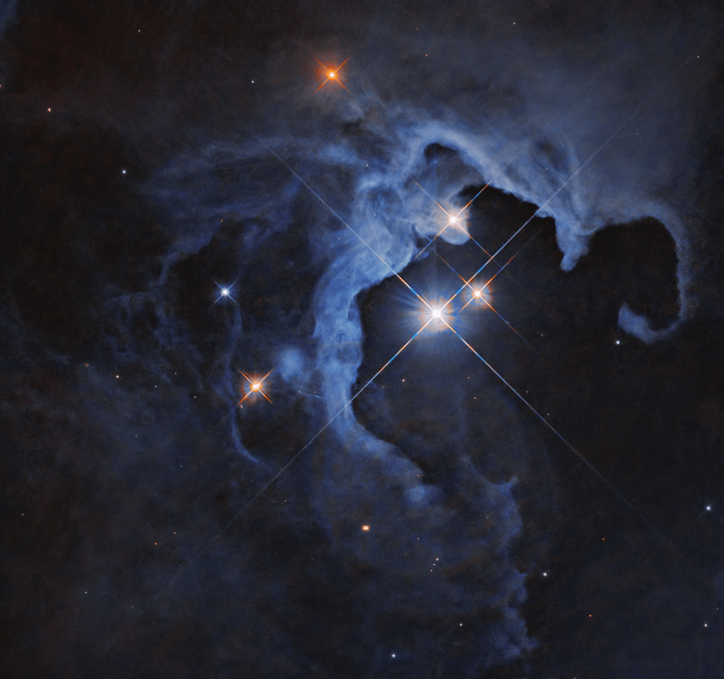 Esta imagen del Hubble muestra un sistema estelar triple en una nebulosa de reflexión, con una nube de gas y polvo curvándose alrededor de varias estrellas brillantes.