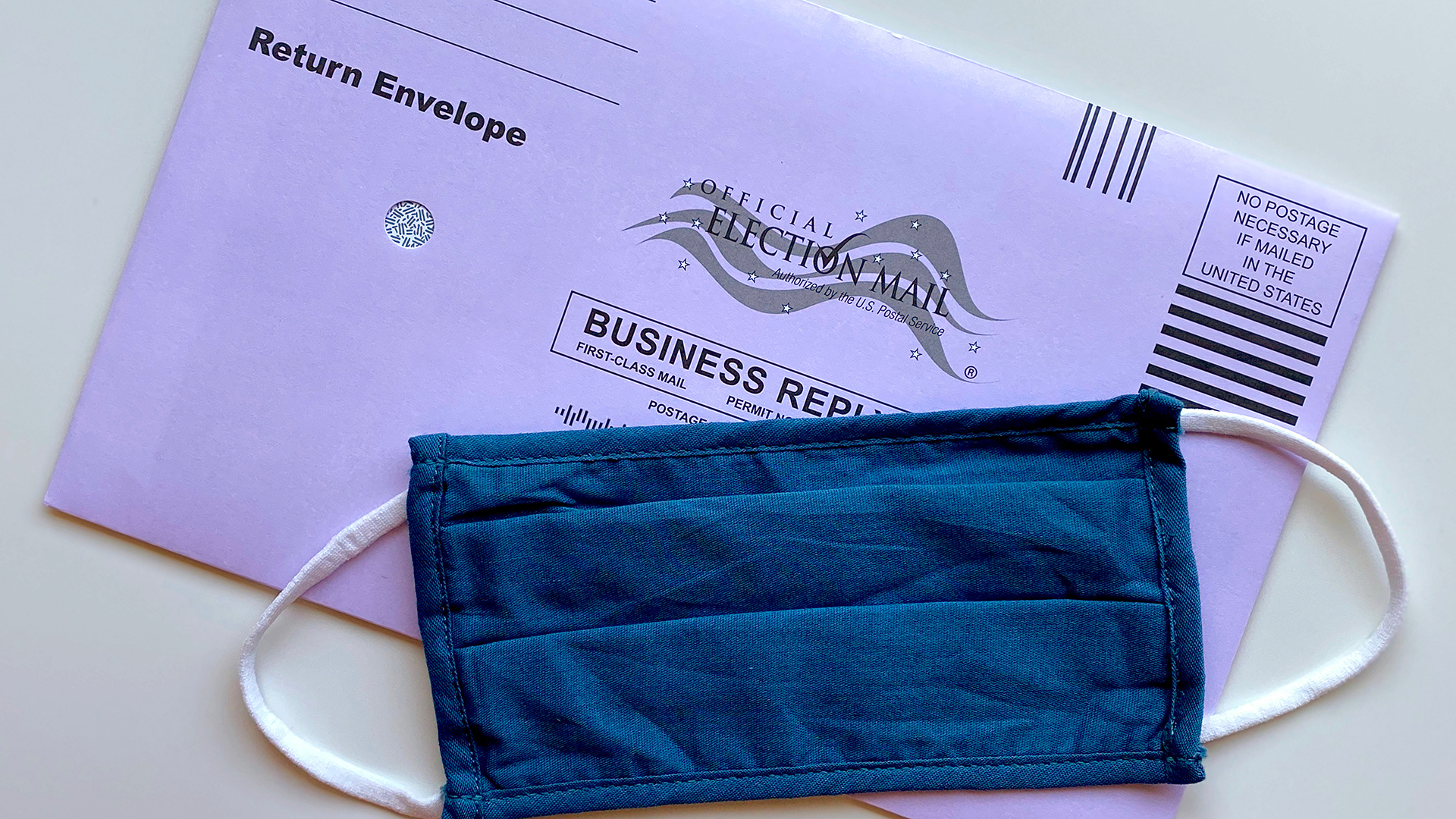 mail-in ballot with blue face mask over it