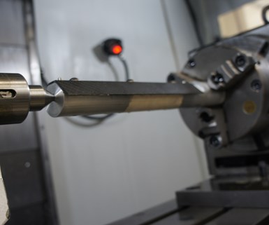 A composite rifle heat shield undergoes operations on a four-axis VMC at composites manufacturer DeltaWing. 