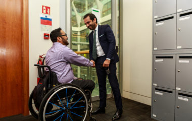 A man in a wheelchair shaking hands with another professional.