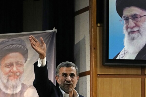Iran's hard-line former President Mahmoud Ahmadinejad waves to the media as he leaves at the conclusion of a press briefing beside portraits of the Supreme Leader Ayatollah Ali Khamenei, top right, and the late President Ebrahim Raisi after registering his name as a candidate for the June 28 presidential election at the Interior Ministry, in Tehran, Iran, Sunday, June 2, 2024. Ahmadinejad registered Sunday as a possible candidate for the presidential election, seeking to regain the country's top political position after a helicopter crash killed the nation's president. (AP Photo/Vahid Salemi)