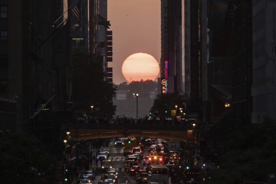 FILE - The sun sets between buildings along 42nd Street in New York during a phenomenon known as "Manhattanhenge," May 30, 2023. Twice per year, New Yorkers and visitors are treated to a phenomenon known as Manhattanhenge, when the setting sun aligns with the Manhattan street grid and sinks below the horizon framed in a canyon of skyscrapers. Manhattanhenge happens for the first time this year on Tuesday, May 28, at 8:13 p.m. and Wednesday, May 29, at 8:12 p.m. (AP Photo/Yuki Iwamura, File)