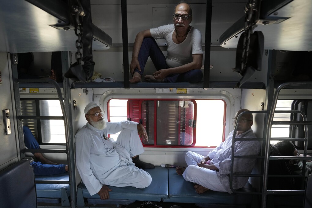 Haji Abdul Subhan, left, and Santosh Kumar Aggarwal, top, travel in a non air-conditioned sleeper compartment of the Thirukkural Express, India, Saturday, April 20, 2024. (AP Photo/Manish Swarup)