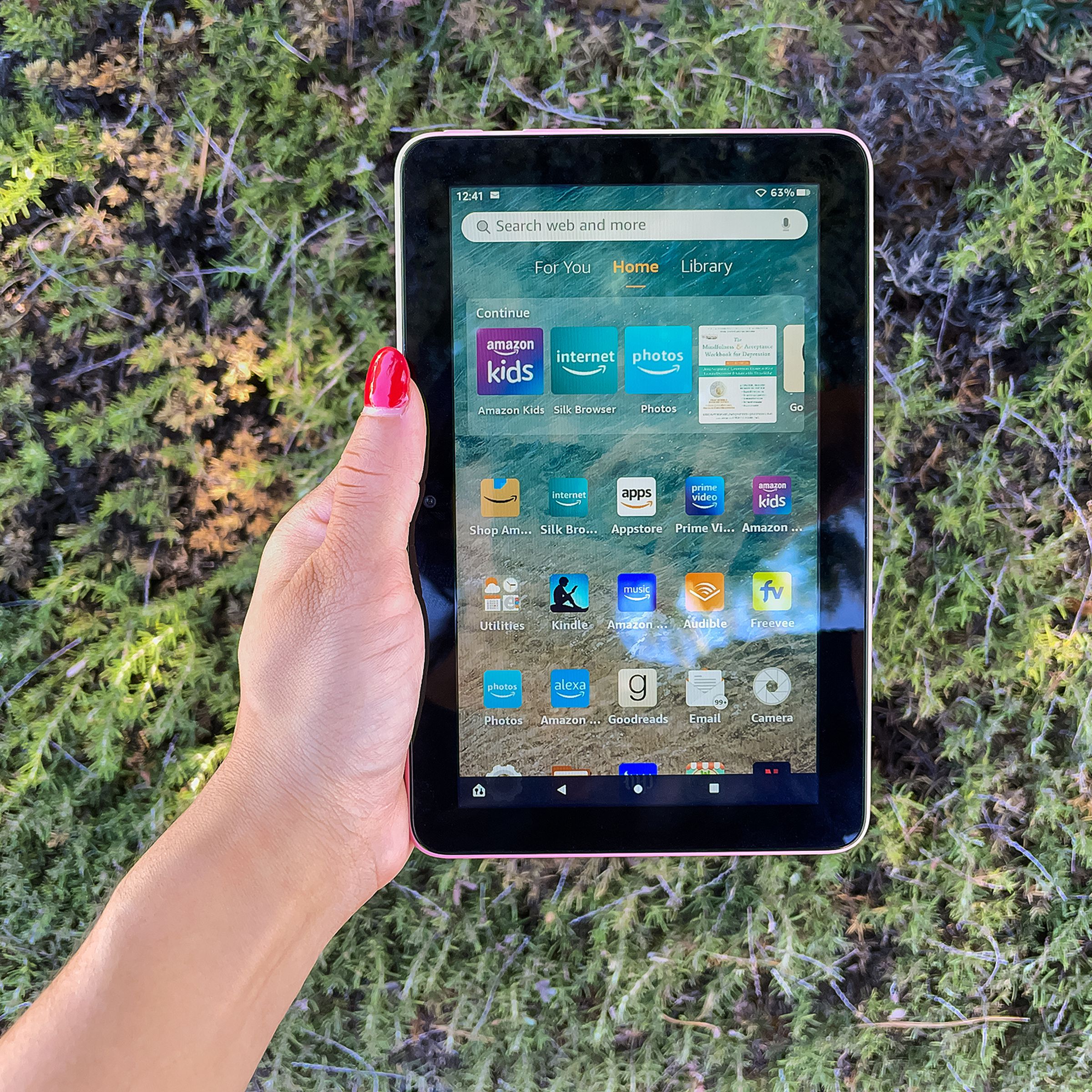 A hand holding Amazon’s Fire 7 tablet while its screen is turned on.