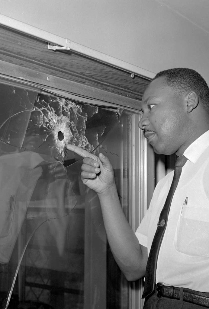 Dr. King inspects a bullet hole in the glass door of his rented cottage in St. Augustine, Florida, on June 5, 1964