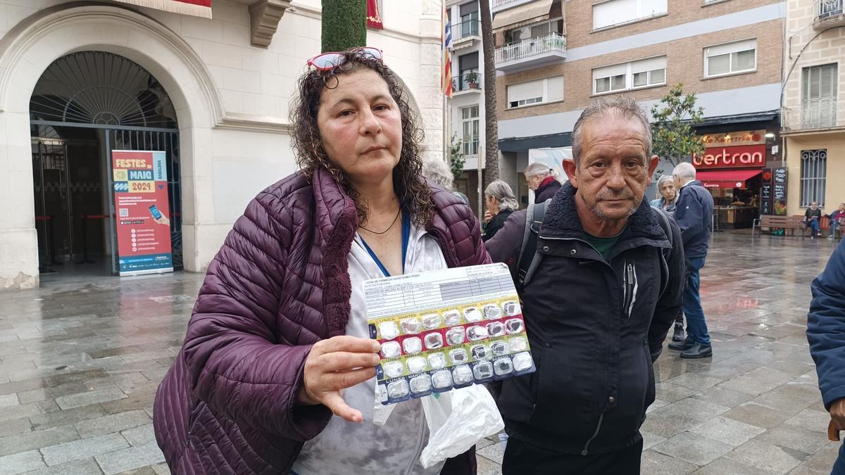 Rocío Caparrós, antigua usuaria del albergue para personas 'sintecho' de Badalona, sostiene el blíster donde guarda las pastillas que ha de tomar. Le acompaña Carlos García, también usuario de Can Vofí Vell