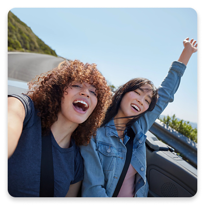 Dos mujeres se toman un selfie en la parte trasera de un auto convertible.