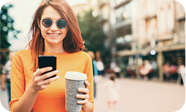 Persona sonriente mirando su teléfono mientras toma café.